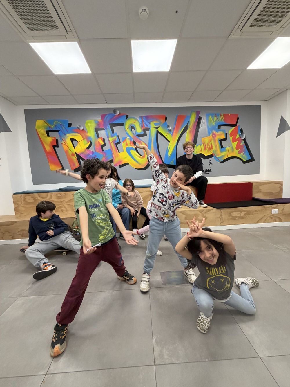 Bambine e bambini in posa davanti al murale con la scritta Freestyle, durante le riprese