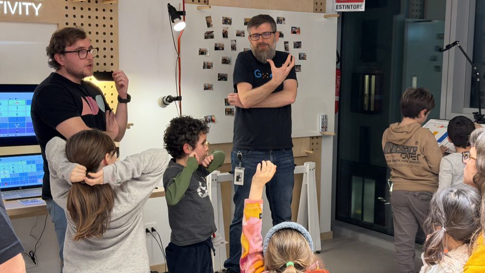 Due tecnici di Google spiegano le tecnologie assistive a un gruppo di bambini in piedi
